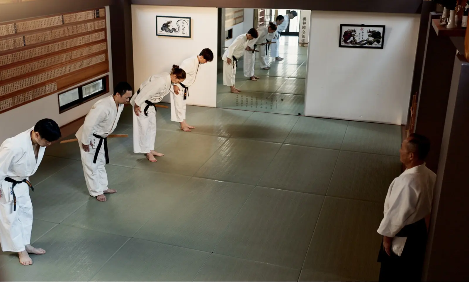 Élèves d'arts martiaux en kimono blanc saluant leur sensei au début de l'entraînement