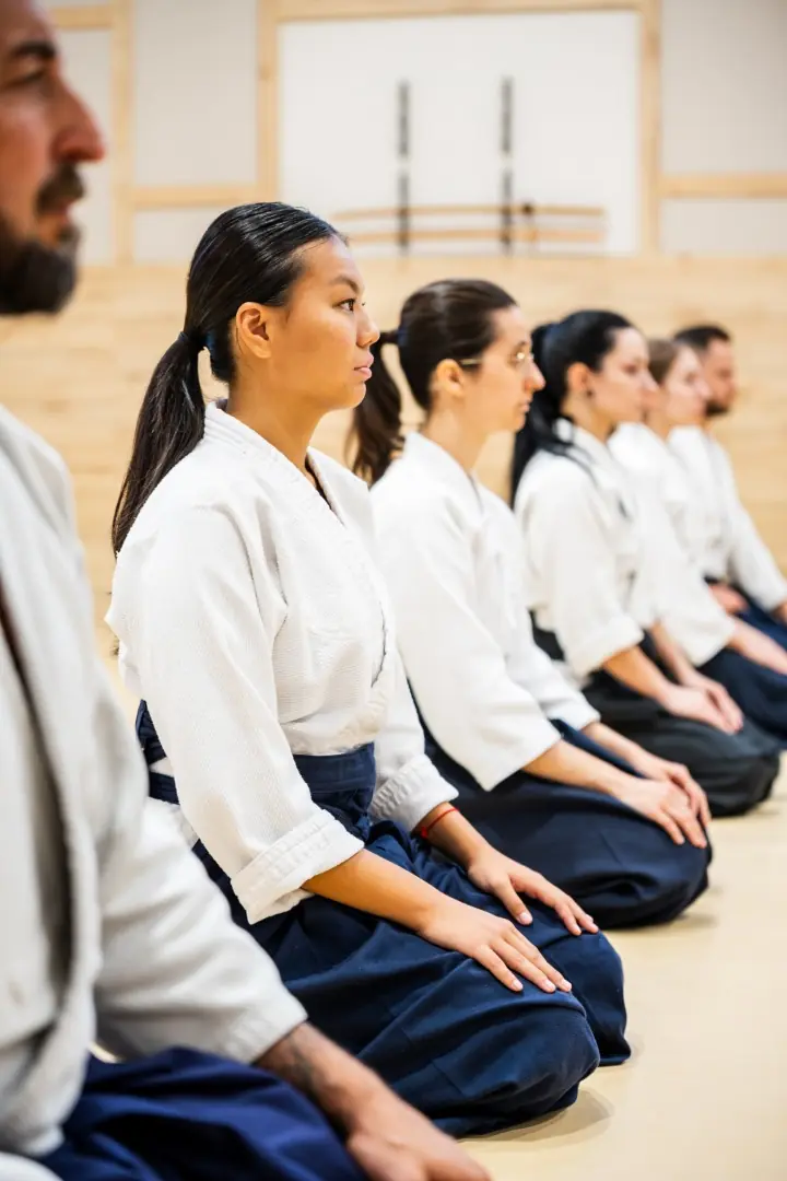 Students kneeling in a line on the mat before training